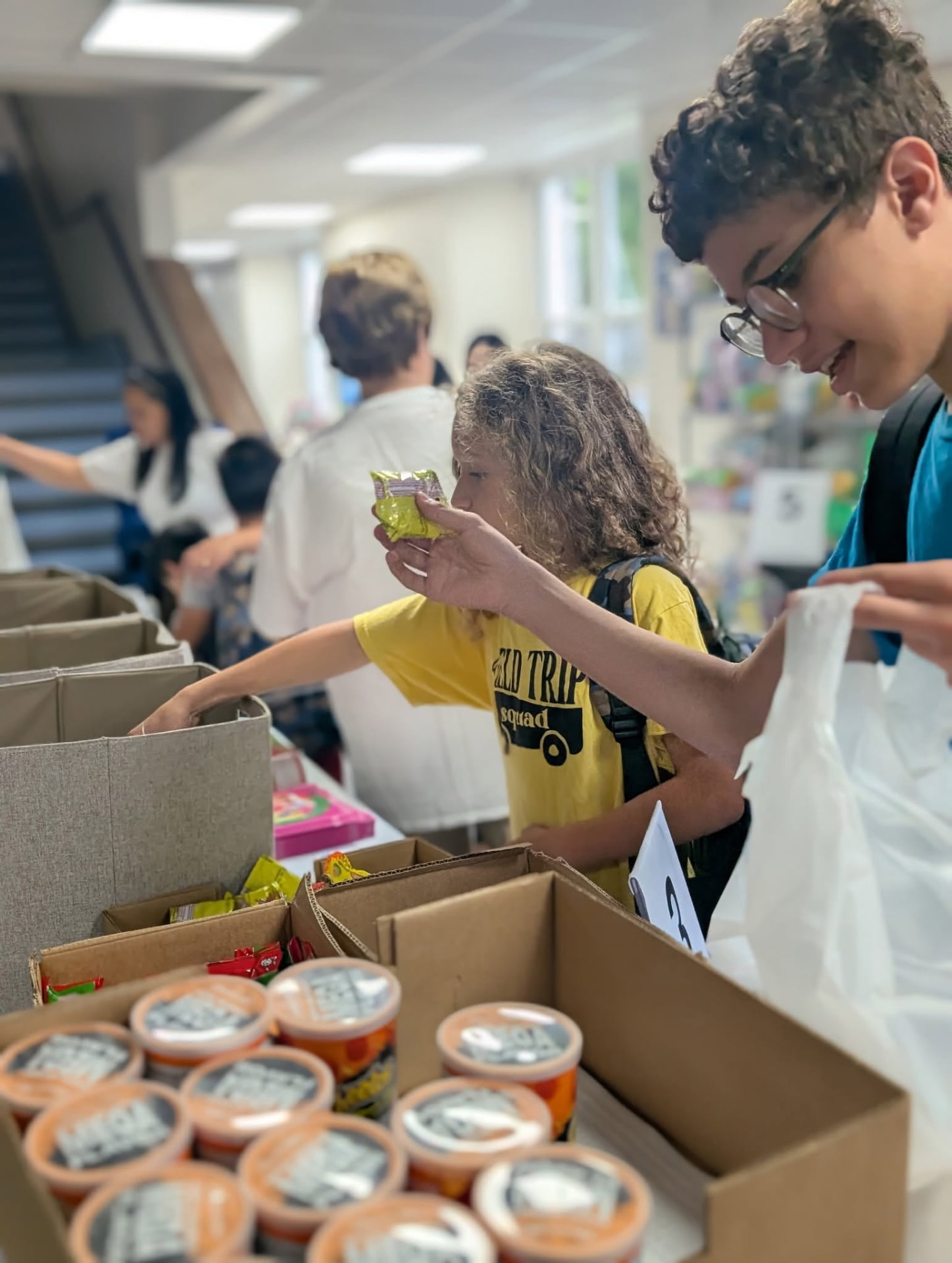 Young volunteers packing food and supplies into bags at the Connect Center